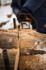 Man cuts firewood in chainsaw in winter