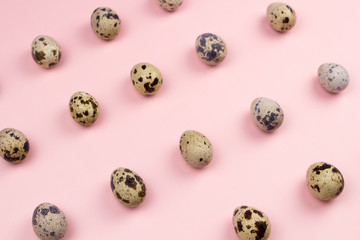 Holiday easter quail eggs on pastel pink background. Close up.