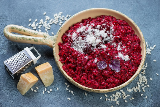 Beetroot risotto topped with baked beetroot slices and grated parmesan cheese, studio shot