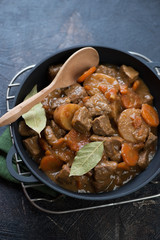 Close-up of Irish traditional beer and beef stew in a cast-iron pan on a metal cooling rack, selective focus, vertical shot