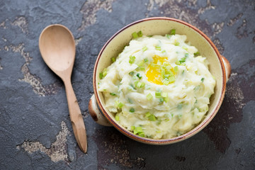 Champ or Irish potato puree with green onion, one of traditional meals for Saint Paddy’s Day, elevated view on a brown stone background