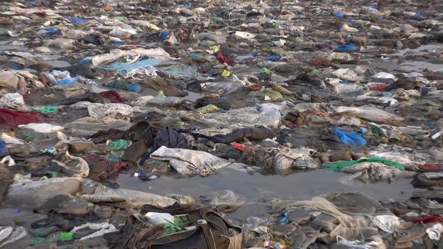Zoom out view of plastic garbage and other pollution at Versova Beach in Mumbai, India 