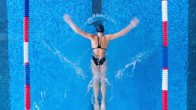 A woman practices her breaststroke and splashes water around. 
