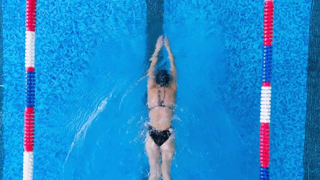 An above view on a swimmers back while she does breaststrokes. 