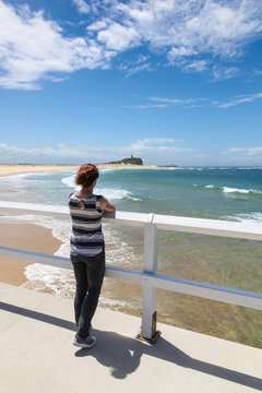 Woman looking at Nobbys Beach - Newcastle Australia. Newcastle is Australia's second oldest city and has many beautiful beaches