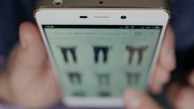 A man looks at the goods in the online clothing store. People using Smartphone, online shopping. Close-up. 4K UHD.