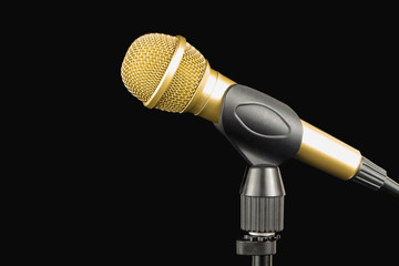 Golden microphone on a stand on a black background