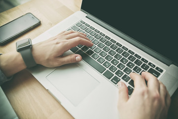 The young woman is sitting at table and working at laptop