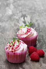 Cupcakes  with fresh raspberries and cream on wooden table