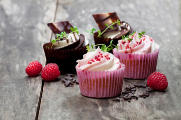 Chocolate  cupcakes with fresh raspberries and cream on wooden table