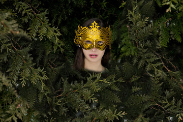 The woman in a Golden Mask among coniferous trees, the forest fantastic fairy