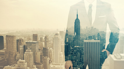 Double exposure ob businessman with hand in pocket and city skyline