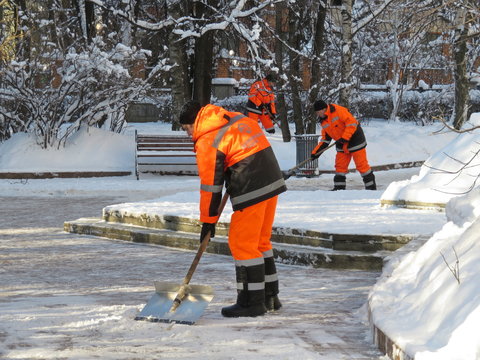 Snow removal in Moscow. Communal services workers in uniform with a shovel clears snow in winter