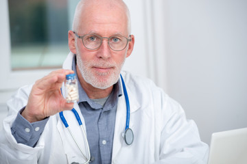 mature doctor with pill in hospital