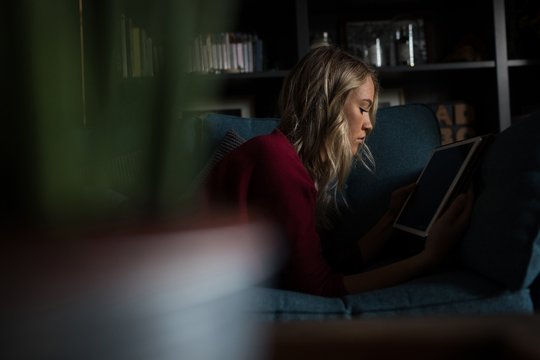 Young woman using tablet while lying on sofa
