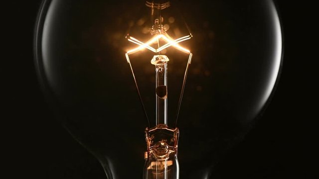 Closeup flashing light bulb on black background