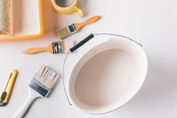 top view of bucket with white paint and tools for repairs on surface