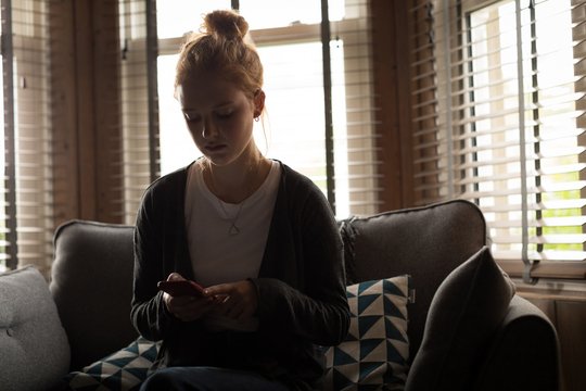 Young woman using her mobile phone on sofa