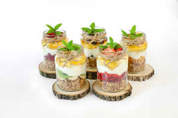 Granola, slices of different fresh fruits, yogurt, honey in jars isolated on white background.