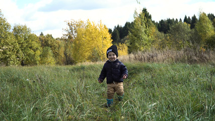 Little boy walks in the park in autumn day. Little boy running on the countryside road.Kid in the park.