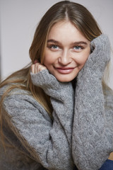 Blue eyed young woman in grey sweater, portrait