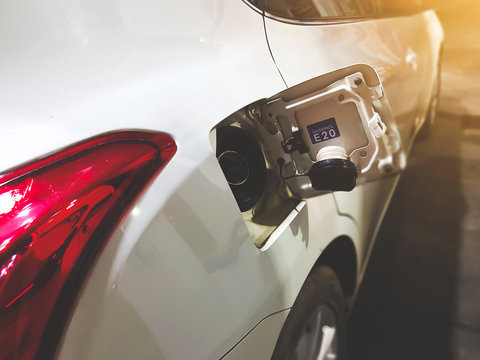 White Car petrol tank cover opened with E20 gassohol label at gas station in the night. 