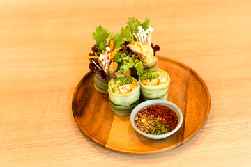 Salad roll of vegetable salad on wooden plate with Thai sauce