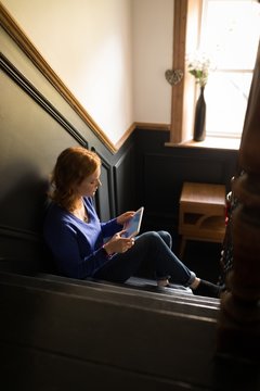 Young woman using tablet while sitting on staircase
