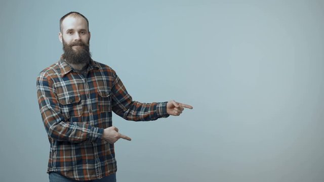 Smiling bearded man pointing at blank copy space for text or product