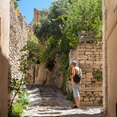  Tourist in alley with souvenir shops in the medieval village Gordes, Vaucluse, Provence-Alpes-Côte d'Azur, Provence, France