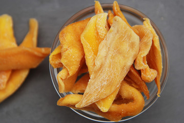 Dried Mango. Organic Dehydrated Mango Fruit Sliced in Glass Bowl over Gray Background. Diet and Healthy Food Concept.