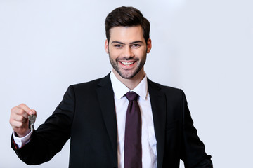 smiling handsome receptionist holding key isolated on white