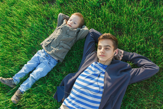 Two brothers, children and teenagers having fun, green meadow