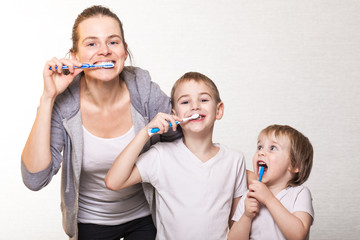 family mom and two blond boys brush their teeth