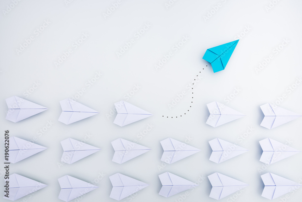 Wall mural group of paper planes in one direction and with one individual pointing in the different way. busine