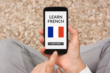 Hands holding smart phone with learn French concept on screen. All screen content is designed by me. Flat lay