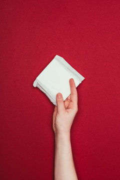 Partial View Of Woman Holding Menstrual Pad In Hand Isolated On Red