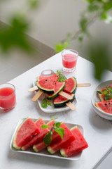 Fresh red smoothie in a glass with sliced pieces of watermelon on table.