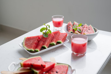 Fresh red smoothie in a glass with sliced pieces of watermelon on table.