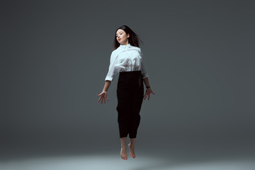 young barefoot asian woman jumping on grey