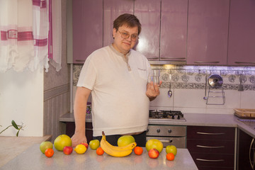 A fat man with a beer belly in a lilac kitchen. Healthy food. A man drinks water from a glass