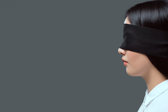 side view of young woman wearing black blindfold isolated on grey
