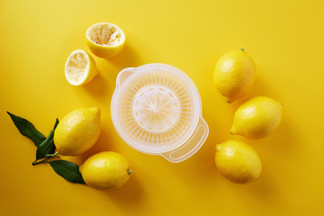 Lemons with lemon squeezer against a yellow background