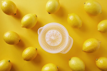 Lemons with lemon squeezer against a yellow background