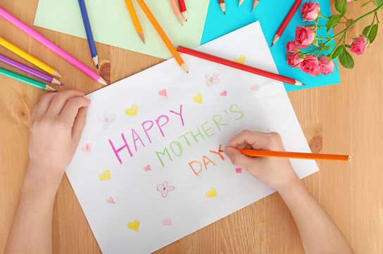 Little girl preparing greeting card for her mommy on Mother's Day at table
