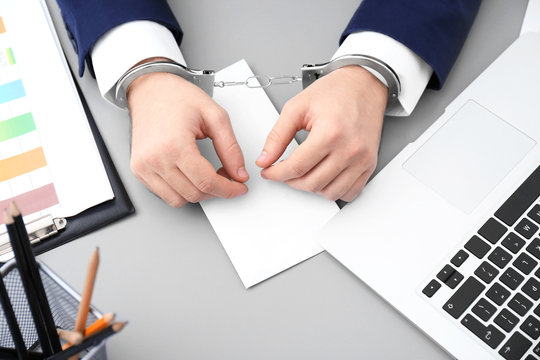 Businessman in handcuffs with bribe at table, closeup