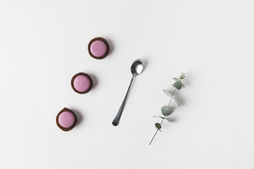 flat lay with arranged macarons, spoon and eucalyptus on white surface