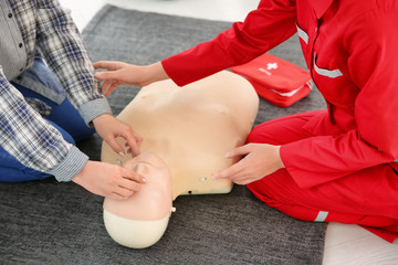Woman practicing CPR on mannequin in first aid class