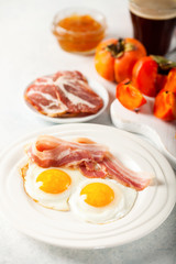 Fried eggs, bacon, a toast, a persimmon