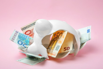 Broken piggy bank with money on color background